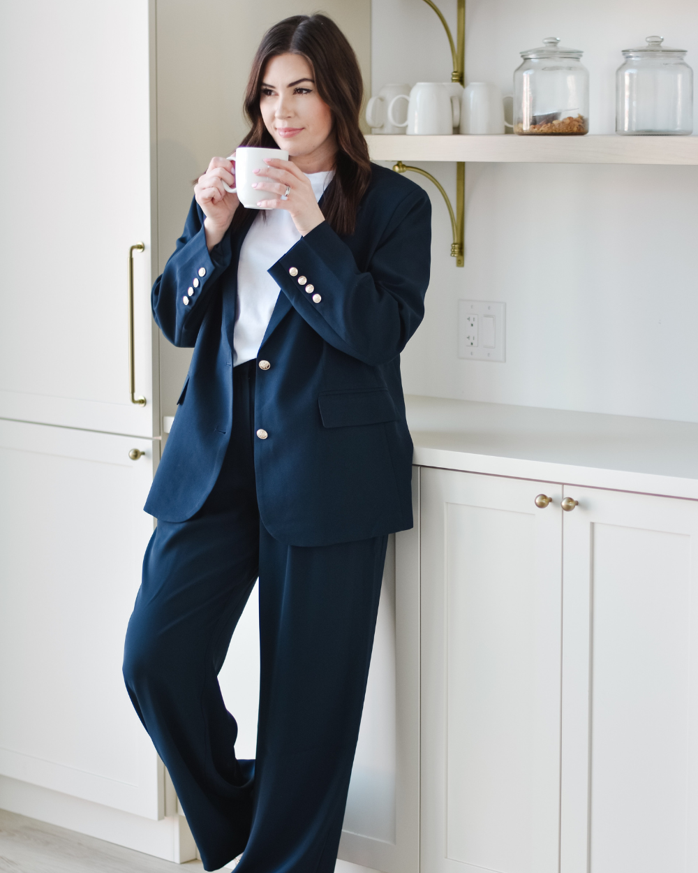 woman wearing a navy suit drinking coffee