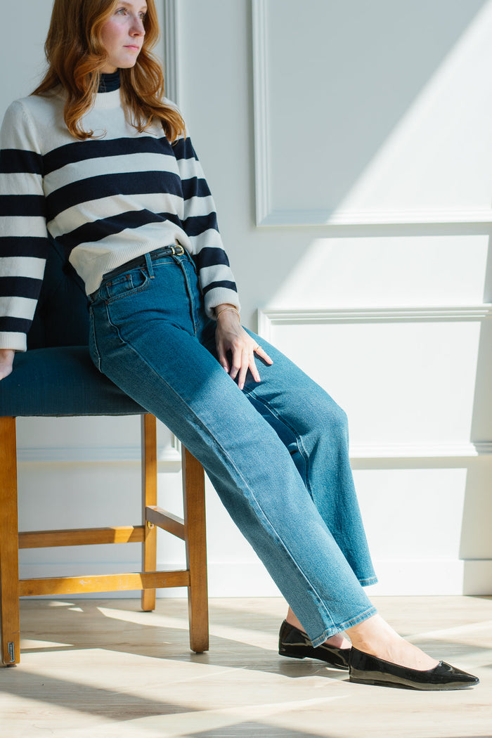 woman wearing jeans and a fall sweater posing on a chair