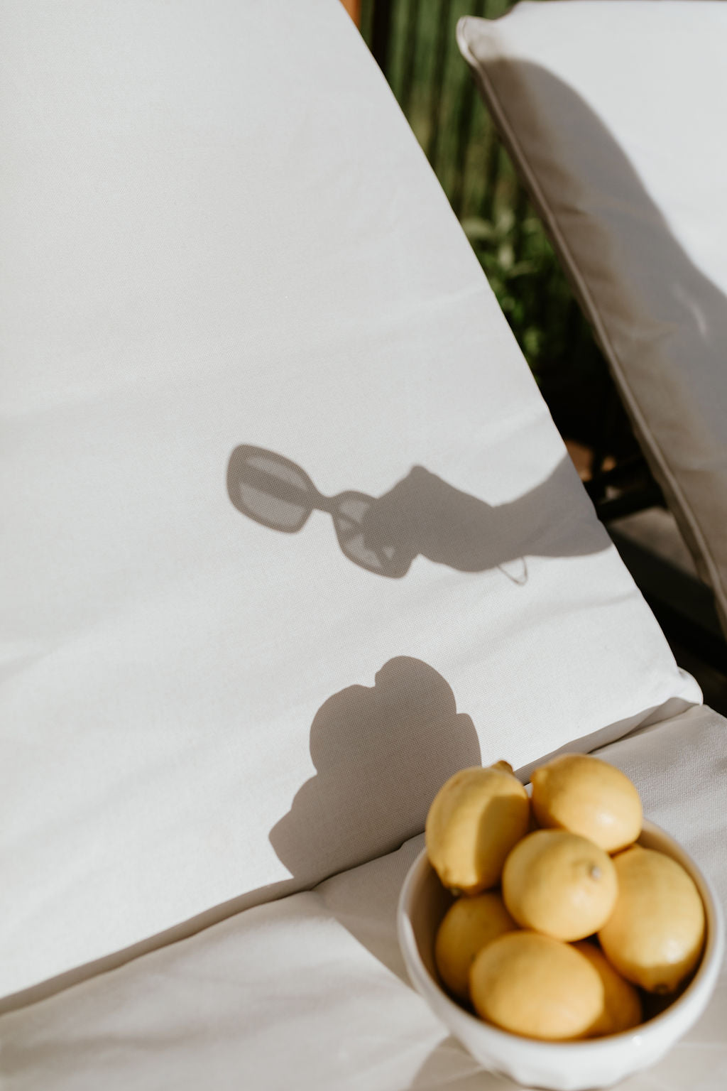 shadow of sunglasses on a beach chair with lemons