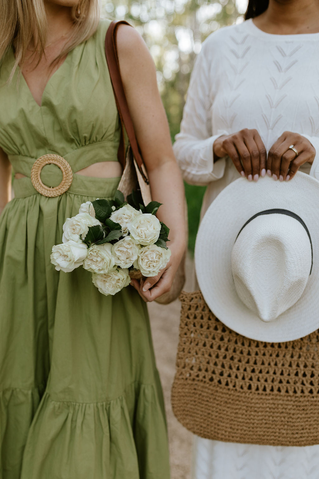 a close up on two women wearing dresses, one is holding flowers the other is holding a sun hat